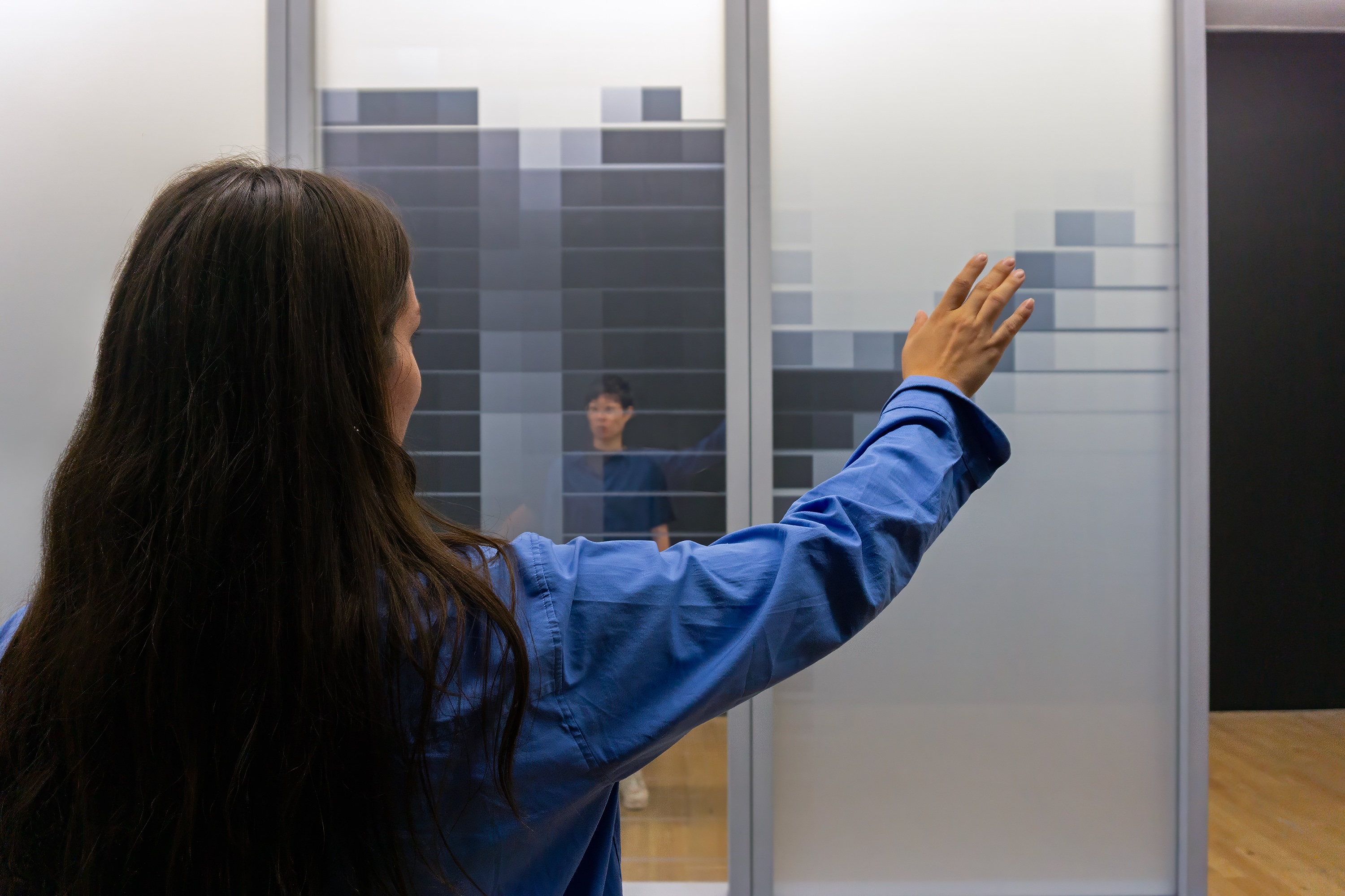 Person interacting with GlassArray glass panels in a gallery